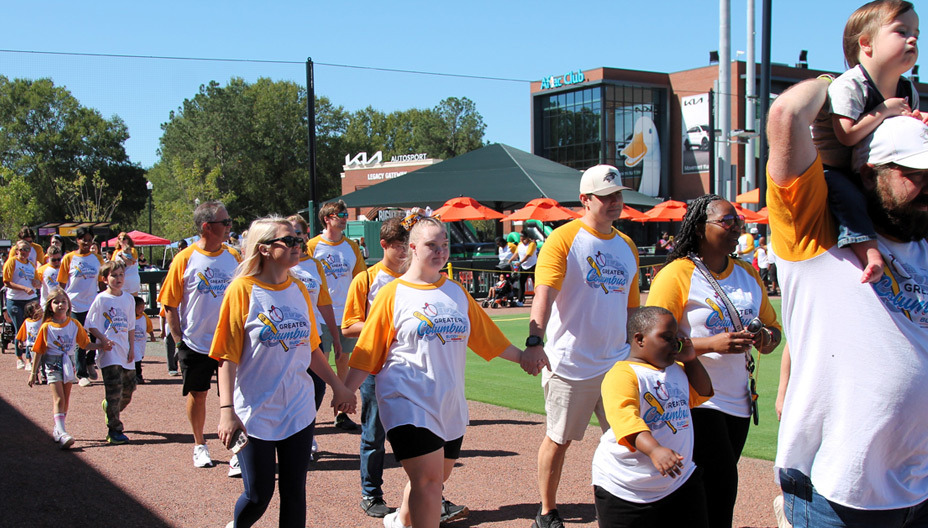 Smiling families walking together for the Buddy Walk hosted at Synovus Park.